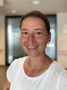 Lächelnde Frau in weißem T‑Shirt vor unscharfem Innenflur