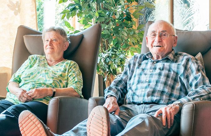 Ältere Frau und älterer Mann sitzen entspannt in Sesseln mit hochgelegten Beinen