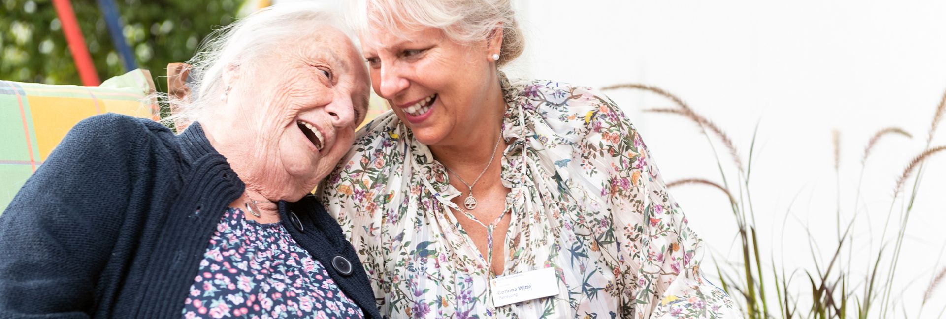 Ältere Frau und jüngere Frau lachen und halten Garn und bunte Decke