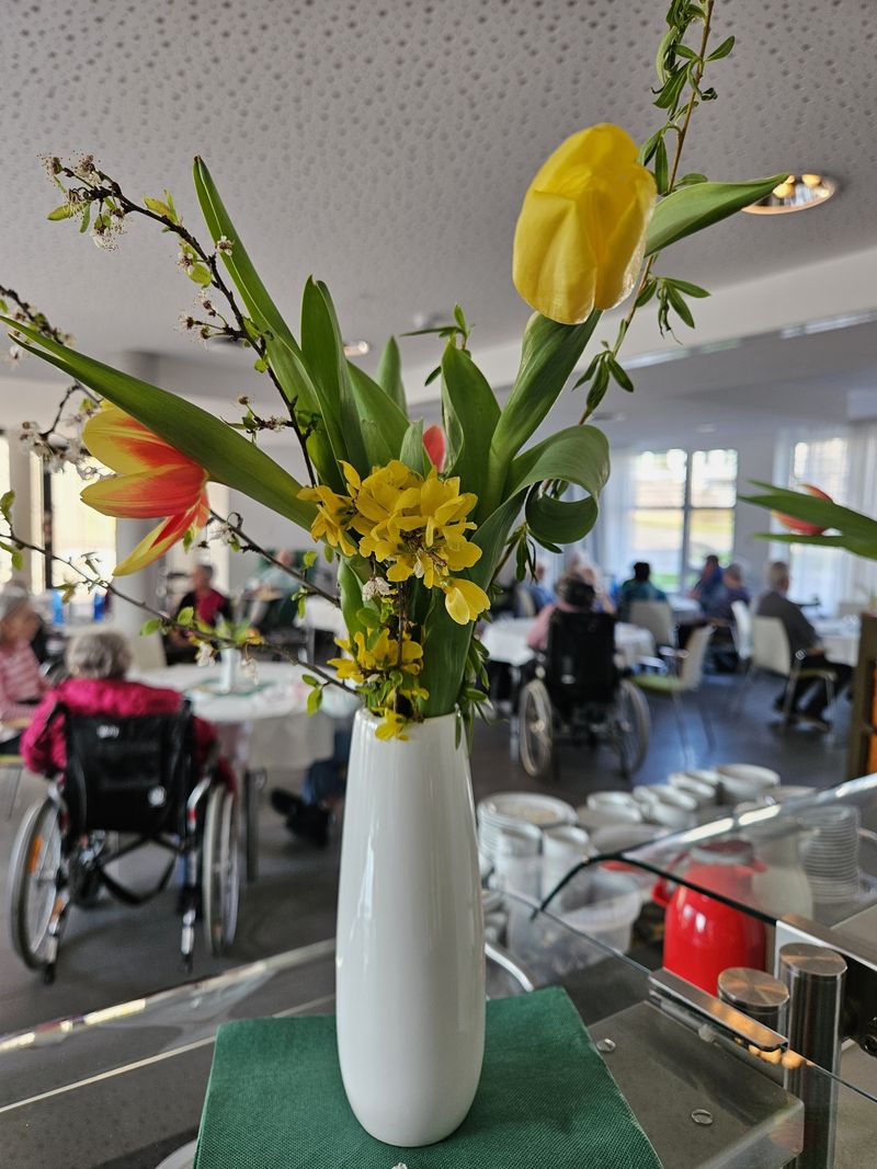 Frühlingsstrauß mit Tulpen in Vase vor Gemeinschaftsraum
